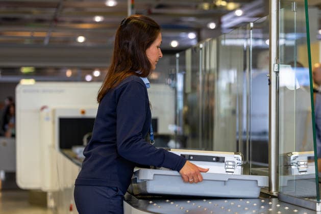 Eröffnung der neuen CT-Kontrollstelle am Airport Nürnberg, Nürnberg, 08.05.2026 Eine Mitarbeiterin bewegt eine Gepäckwanne mit Transportkoffer auf der Fördertechnik der neuen CT-Kontrollstelle am Airport Nürnberg. Im Hintergrund ist ein CT-Scanner von Smiths Detection zu sehen. Nürnberg Bayern Deutschland