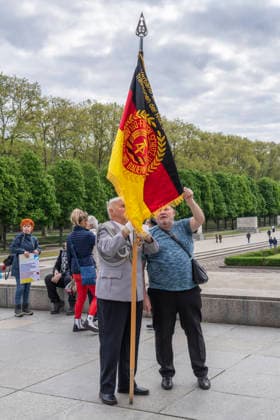 Ein ehemaliger Offizier der Nationalen Volksarmee (NVA) der DDR mit einer DDR-Fahne am 9. Mai, dem Tag des Sieges, am Sowjetischen Ehrenmal im Treptower Park in Berlin-Treptow.