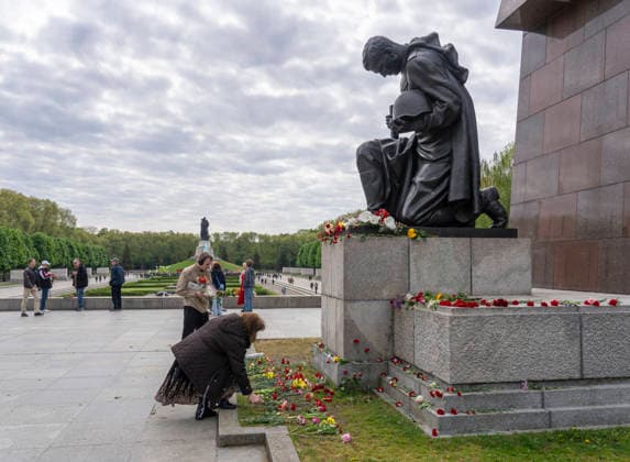 Besucher legen Blumen am kniehenden Rotarmisten nieder am 9. Mai, dem Tag des Sieges, am Sowjetischen Ehrenmal im Treptower Park in Berlin-Treptow.