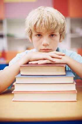 I cant believe I have to read this much. A serious young boy sitting at his desk and leaning his chin on a stack of books (License=RF) ,model released, Symbolfoto  Copyright: xZoonar.com KasperxRavlox 20241838 ,model released, Symbolfoto ,property released