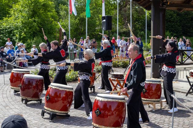 Teilnehmer einer japanischen Taiko-Trommelgruppe treten bei einer Kulturveranstaltung im Freien auf. Traditionelle Trommelrhythmen und choreografierte Bewegungen ziehen zahlreiche Besucher an. Traditionelles Japanisches Frühlingsfest im Botanischen Garten Augsburg. Das Event im Rahmen des 90-jährigen Garten-Jubiläums