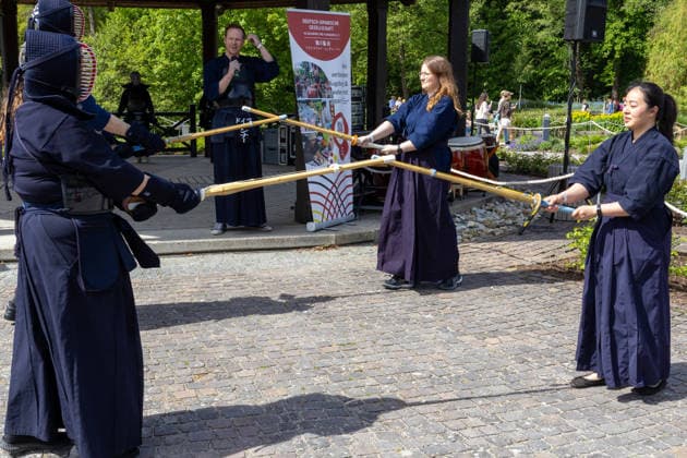 Teilnehmer in japanisch inspirierten Kostümen und Kendo-Ausrüstung präsentieren Schwertkampf und Rollenspiel. Traditionelles Japanisches Frühlingsfest im Botanischen Garten Augsburg. Das Event im Rahmen des 90-jährigen Garten-Jubiläums