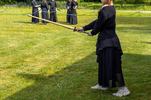 Teilnehmerin mit Trainingsschwert bei einer Vorführung japanischer Kampfkunst auf einer Wiese. Die Übung verbindet Konzentration, Disziplin und traditionelle Techniken des asiatischen Schwertkampfs. Traditionelles Japanisches Frühlingsfest im Botanischen Garten Augsburg. Das Event im Rahmen des 90-jährigen Garten-Jubiläums