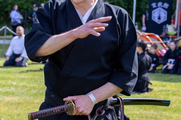 Teilnehmer einer japanischen Kampfkunstvorführung hält ein Katana während einer Demonstration traditioneller Schwerttechniken. Traditionelles Japanisches Frühlingsfest im Botanischen Garten Augsburg. Das Event im Rahmen des 90-jährigen Garten-Jubiläums