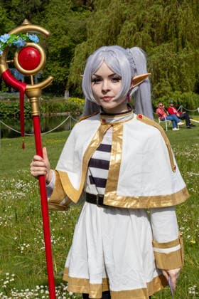 Cosplayerin mit weißem Fantasykostüm, Elfenohren und verziertem Zauberstab bei einer Veranstaltung im Freien. Die Darstellung orientiert sich an Anime-, Manga- und Fantasyfiguren der internationalen Cosplay-Szene. Traditionelles Japanisches Frühlingsfest im Botanischen Garten Augsburg. Das Event im Rahmen des 90-jährigen Garten-Jubiläums