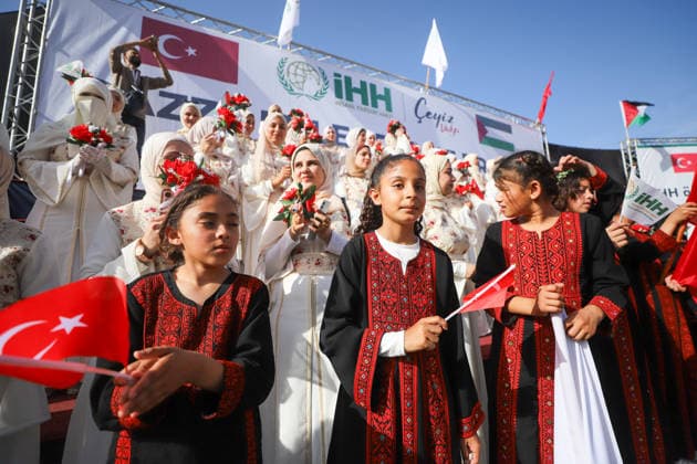 Mass Wedding Gaza City May 11 Girls wearing traditional embroidered dresses hold Turkish flags in front of a stage of brides during a mass wedding celebration in Gaza City, Gaza Strip, on May 11, 2026. The mass wedding celebration for 50 grooms, identified by organizers as orphans of conflict casualties, is sponsored by the Turkish Humanitarian Relief Foundation (IHH). Gaza Gaza Strip Palestinian Territories Copyright: xAhmedxAlxArinix