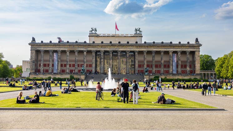 Altes Museum Berlin Lustgarten mit Brunnen und Frühlingstreiben, Berlin, 10.05.2026 Frontansicht des Alten Museums am Lustgarten in Berlin-Mitte mit dem Brunnen im Vordergrund. Zahlreiche Menschen erholen sich auf der Rasenfläche im Frühlingssonnenschein. An der Säulenfassade sind Banner zur Ausstellung Antike zu sehen. Berlin-Mitte Berlin Deutschland