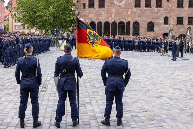 Öffentliches Gelöbnis der Bundeswehr auf dem Sebalder Platz, Nürnberg, 13.05.2026 Fahnenträger präsentieren die Truppenfahne mit Bundesadler vor den angetretenen Rekruten des Luftwaffenausbildungsbataillons Germersheim. Im Vordergrund eine Soldatin als Teil der Fahnenabordnung. Nürnberg Bayern Deutschland