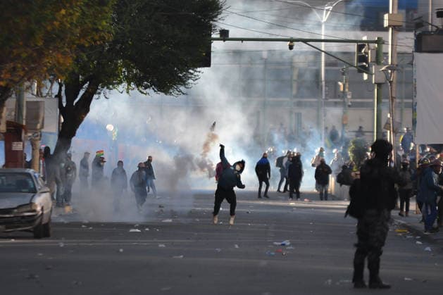 Miners attempt to break through police cordon in La Paz LA PAZ, BOLIVIA - MAY 14: A miner throws back a tear gas canister as a police officer watches during clashes between mining cooperatives and security forces in downtown La Paz, Bolivia, on May 14, 2026. Carlos Sanchez Navas Anadolu La Paz Bolivia. Editorial use only. Please get in touch for any other usage.  Copyright: x2026xAnadoluxCarlosxSanchezxNavasx