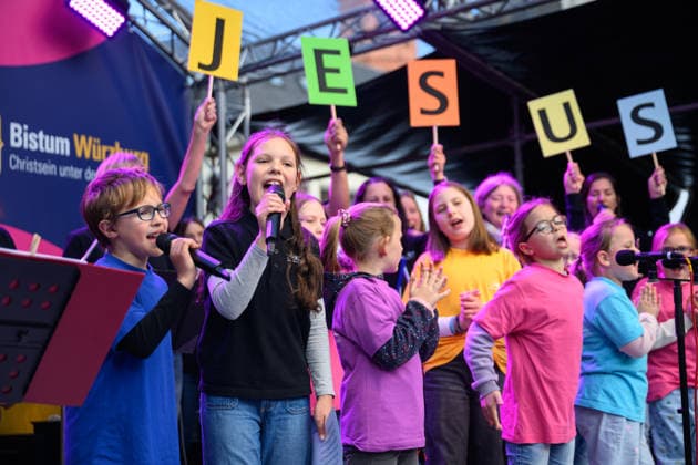 Ein Kinderchor auf der Buehne am Oberen Markt auf dem Katholikentag in Wuerzburg (Foto vom 15.05.2026). Bis Sonntag werden beim 104. Deutschen Katholikentag unter dem biblischen Leitwort Hab Mut, steh auf! mehrere zehntausend Teilnehmende zu insgesamt 900 Veranstaltungen erwartet. Das Treffen soll angesichts von Krieg, Klimawandel, sozialer Spaltung sowie Vertrauenskrisen in Politik und Kirche dazu ermutigen, nach Wegen fuer die Zukunft zu suchen. (Siehe epd-Meldung vom 15.05.2026) EDITORIAL USE ONLY