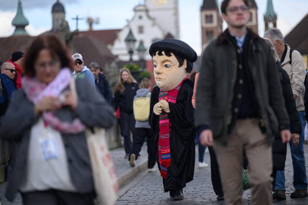 Eine Person mit Luther-Kostuem auf der Alten Mainbruecke waehrend dem Katholikentag in Wuerzburg (Foto vom 15.05.2026). Bis Sonntag werden beim 104. Deutschen Katholikentag unter dem biblischen Leitwort Hab Mut, steh auf! mehrere zehntausend Teilnehmende zu insgesamt 900 Veranstaltungen erwartet. Das Treffen soll angesichts von Krieg, Klimawandel, sozialer Spaltung sowie Vertrauenskrisen in Politik und Kirche dazu ermutigen, nach Wegen fuer die Zukunft zu suchen. (Siehe epd-Meldung vom 15.05.2026) EDITORIAL USE ONLY