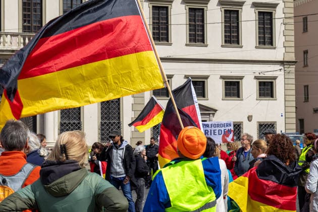 Demonstration gegen die aktuelle Bundesregierung unter Bundeskanzler Friedrich Merz in Augsburg. Unter dem Motto: Merz muss weg! Mehrere Demonstrationsteilnehmer tragen und schwenken Deutschlandflaggen während der Kundgebung im Stadtzentrum von Augsburg