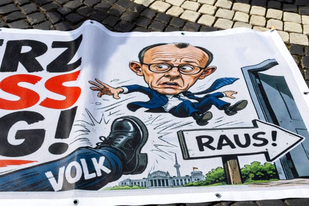 Demonstration gegen die aktuelle Bundesregierung unter Bundeskanzler Friedrich Merz in Augsburg. Unter dem Motto: Merz muss weg! Banner mit Aufschrift: MERZ MUSS WEG! Mit Illustration von einem Fuß auf dem VOLK steht und einer Illustration von Bundeskanzler Friedrich Merz (CDU) der durch eine Tür fliegt mit einem Schild mit Aufschrift: RAUS!