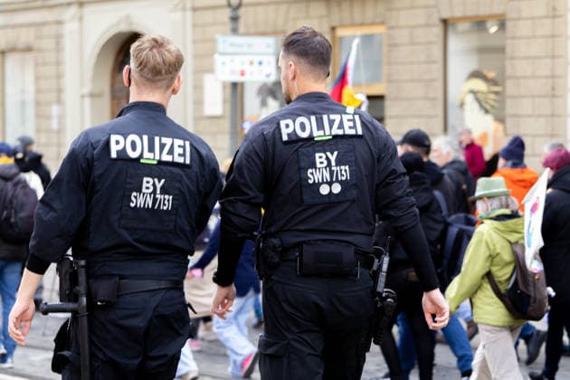 Demonstration gegen die aktuelle Bundesregierung unter Bundeskanzler Friedrich Merz in Augsburg. Unter dem Motto: Merz muss weg! Zwei Polizisten vor vorbeilaufenden Demonstraten zur Absicherung