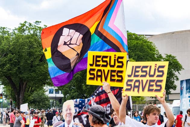 May 17, 2026, Washington, District Of Columbia, USA: Attendees holding Ã¢â‚¬oeJesus SavesÃ¢â‚¬Â signs stand in front of an inclusive protest flag outside the Ã¢â‚¬oeRededicate 250Ã¢â‚¬Â event in the National Mall. Washington USA - ZUMAh196 20260517_znp_h196_019 Copyright: xTomxHudsonx