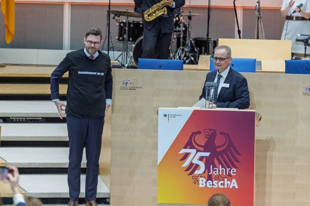 Festakt 75 Jahre Beschaffungsamt des BMI in Bonn Präsident des BeschA Dr. Alexander EISVOGEL überreicht Staatssekretär Sebastian WÜSTE ein T-Shirt des Beschaffungsamtes - Festakt zum 75-jährigen Bestehen des Beschaffungsamtes des BMI im ehemaligen Plenarsaal des Deutschen Bundestages, der heute Teil des World Conference Center Bonn ist. Das Beschaffungsamt gilt als größter ziviler Beschaffer des Bundes und beschafft unter anderem für das Technische Hilfswerk. Bonn Gronau Rheinland-Pfalz Deutschland Copyright: xMarcxJohnx