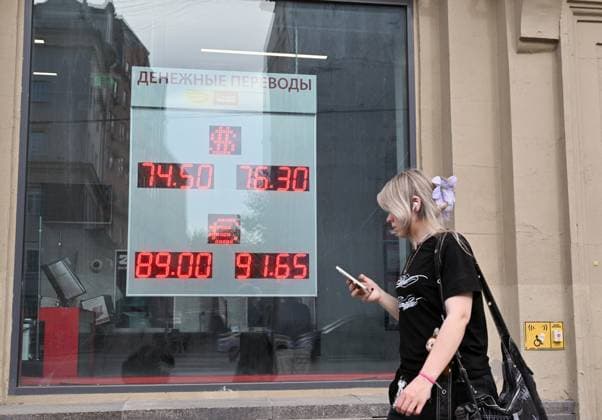 Russia Economy 9168271 18.05.2026 A girl walks past a board showing currency exchange rates for the U.S. dollar and the euro against the Russian rouble in Moscow, Russia. Ilya Pitalev Sputnik Moscow Russia  Copyright: xIlyaxPitalevx