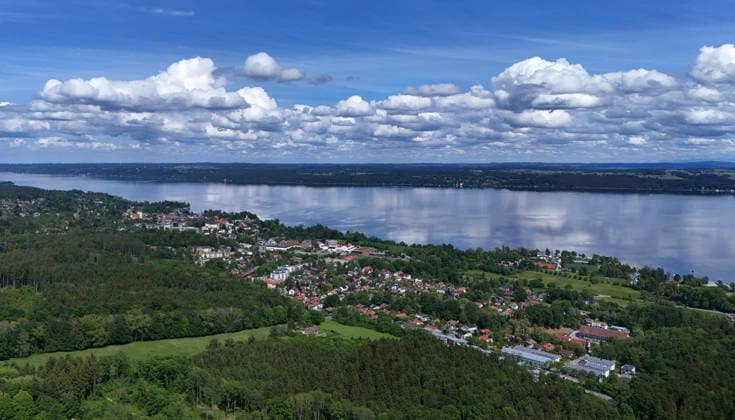 Ein Frühsommertag bei Tutzing (Landkreis Starnberg). Hier der Blick hoch über der Ilkahöhe auf Oberzeismering, das die Ortschaft mit dem Starnberger See und Schönwetterwolken