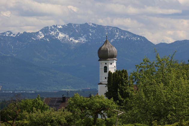 Ein Frühsommertag bei Tutzing (Landkreis Starnberg). Hier der Blick von der Ilkahöhe auf den Kirchturm des Nikolauskircherl, im Hintergrund die Benediktenwand
