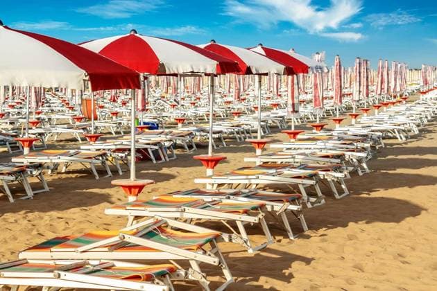red and white umbrellas and sunlongers on the sandy beach in Italy Copyright: xartushx Panthermedia69126138.jpg