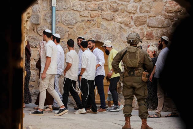 Hebron Israeli Settlers Tour May 23 An armed Israeli soldier stands guard while Israeli settlers continue their tour in the Old City of Hebron, in the occupied West Bank, on May 23, 2026. The area is routinely secured by military forces to escort settlers touring the city, amid ongoing tensions regarding settlement expansion near the Ibrahimi Mosque. Hebron West Bank Palestinian Territories Copyright: xMosabxShawerx