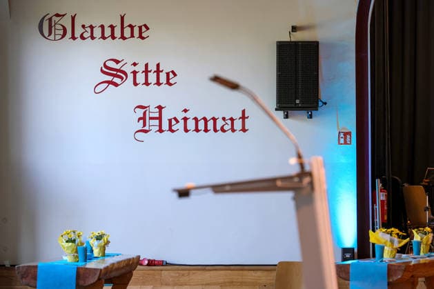 27.05.2026, Politik, Bundeskanzler Friedrich Merz (CDU) zu Gast als Festredner beim Festakt in der Schützenhalle Hüsten bei Arnsberg. 80 Jahre Neheim-Hüstener Programm. Wandaufschrift Schriftzug Glaube Sitte Heimat Nordrhein-Westfalen Deutschland