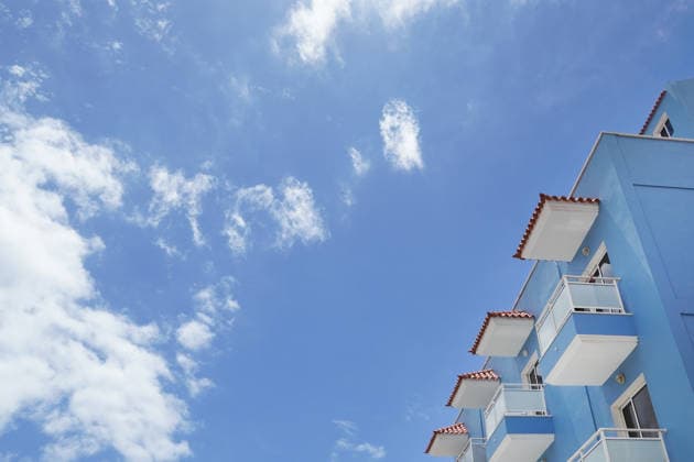 Thema Sonne, Strand und Meer, modernes Hotel und Schönwetterwolken aus der Untersicht als Symbolbild für Sommerurlaub am Meer, Strandurlaub, All Inclusiv Urlaub, z.B. Kanaren, Mittelmeerinseln