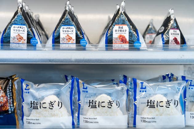 Verpackte Onigiri und Reisbällchen werden in einer Kühltheke eines japanischen Convenience Stores angeboten. Die gefüllten Reis-Snacks gehören zu den beliebtesten schnellen Mahlzeiten im Alltag Japans
