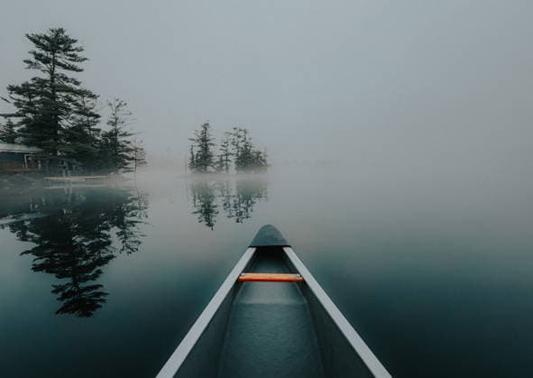 Canoe glides across a still lake in heavy fog in early morning Buck Lake, Ontario, Canada CR_DOHO260604G-2040778-01