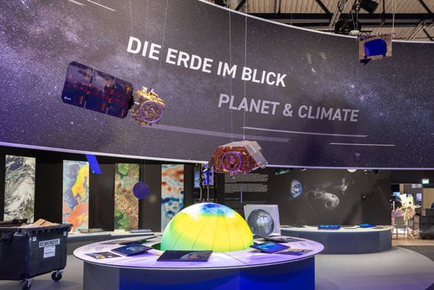 Presserundgang auf der ILA Berlin 2026, Berlin, 09.06.2026 Ausstellungsstand der ESA (European Space Agency) mit dem Themenbereich Die Erde im Blick - Planet & Climate . Haengende Satellitenmodelle, grossformatige Erdbeobachtungsbilder und ein beleuchtetes Erdmodell praegen die Praesentation.