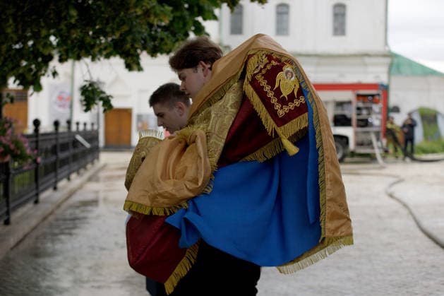 Two young men hold religious banners at the Kyiv Pechersk Lavra, where the roof of the Dormition Cathedral caught fire during a massive Russian combined attack, Kyiv, Ukraine, June 15, 2026. The Russian army launched a large-scale assault on the Ukrainian capital with missiles and strike drones, killing four people and injuring 28, including children and a pregnant woman. At least 140,000 consumers were left without electricity due to damage to power grids. Residential buildings, the Kyiv Pechersk Lavra, the Mystetskyi Arsenal Museum Complex, the Dovzhenko Film Studio, and the building of the High Anti-Corruption Court sustained damage. (Photo by Marianna Kotyk Ukrinform) Massive Russian attack damages Kyiv Pechersk Lavra and Mystetskyi Ars Copyright: xMariannaxKotykx