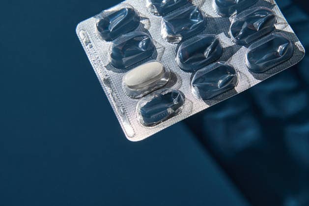 Eine einzelne weiße Tablette, die teilweise in einer metallischen Blisterverpackung auf tiefblauem Hintergrund sitzt Single White Tablet Partially Seated In Metallic Blister Pack On Deep Blue Background With Reflective Highlights And Defined Shadows Under Controlled Studio Illumination For Medical Product Display. (License=RF) Copyright: xZoonar.com ElenaxSafonovax 25294500