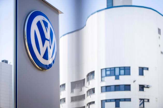 Symbolbild Volkswagen Osnabrück. VW Logo am Tor 2 durch den Zaun fotografiert mit weißem Werksgebäude im Hintergrund. VW-Werk in Osnabrück 11.07.2026 Symbolbild VW Osnabrück