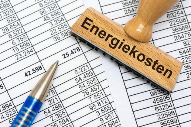 Energiekosten und Energiepreise Ein Holzstempel ist beschriftet mit dem Aufdruck Energiekosten als Symbolbild für steigende Kosten für Energie in Wirtschaft, Industrie und Handel - FOTOMONTAGE - NUR FÜR REDAKTIONELLE VERWENDUNG -