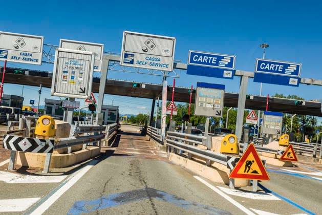 Blick aus einem Fahrzeug auf die Einfahrt einer Autobahnmautstelle. Italien. An einer Mautstelle in Italien