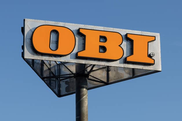 OBI-Firmenschild auf Pylonmast, Nürnberg, 24.07.2026 Weithin sichtbares Firmenschild des Baumarkts OBI auf einem Pylonmast vor blauem Himmel. Das orange-silberne Logo ist das markante Erkennungszeichen der Baumarktkette. Nürnberg Bayern Deutschland