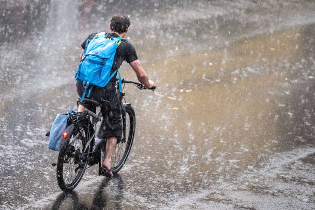 Starkregen in Göttingen 03.08.2026, Göttingen --- Eine Radfahrerin fährt während eines Starkregens durch eine Straße in Göttingen.. Göttingen Niedersachsen Deutschland