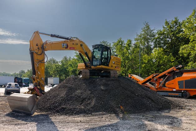 Baustart Cargo ‹Center 3 am Flughafen Nürnberg, Nürnberg, 04.08.2026 Ein Kettenbagger der Marke CAT steht auf einem Schotterhaufen und markiert den Baustart des neuen Cargo Centers 3 (CCN 3) am Flughafen. Mit dem Neubau reagiert der Flughafen auf die anhaltend hohe Nachfrage nach Logistikflächen. Im Hintergrund ist eine orangefarbene Siebanlage zu sehen. Nürnberg Flughafen Bayern Deutschland