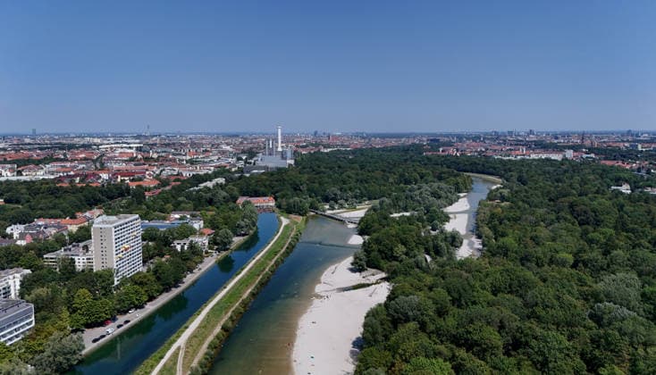 Ein Sommertag in der Landeshauptstadt München. Hier der Blick auf die auf die Isar und den Isar Werkskanal (li.) sowie den Flaucher, Badegelände, Kiesstrand, sowie die Skyline der Stadt München mit Blick Richtung Norden, Stadtblick, Häusermeer, Erholungsgebiet, Sonnen, baden, Abkühlen