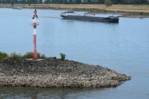 Historisches Niedrigwasser im Rhein, die Wasserschutzpolizei Duesseldorf meldet mit 23cm den niedrigsten in Duesseldorf gemessenen Rheinpegel, Tiefer Wasserstand, steiniges Flussufer, eine weit aufragende rote Ufermarkierung, im Hintergrund ein Frachtschiff, Duesseldorf, 04.08.2026
