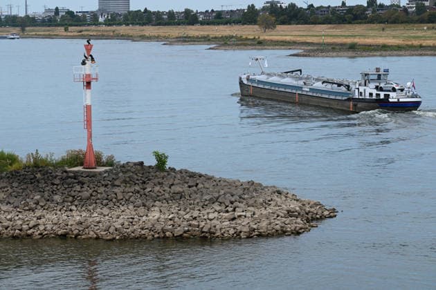Historisches Niedrigwasser im Rhein, die Wasserschutzpolizei Duesseldorf meldet mit 23cm den niedrigsten in Duesseldorf gemessenen Rheinpegel, Tiefer Wasserstand, steiniges Flussufer, eine weit aufragende rote Ufermarkierung, im Hintergrund ein Frachtschiff, Duesseldorf, 04.08.2026