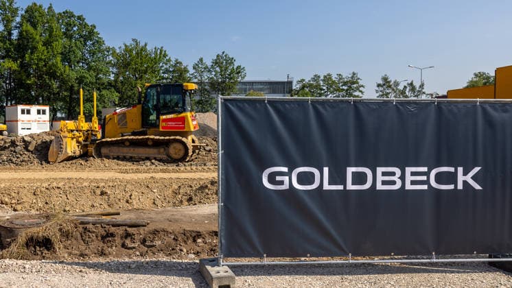 Baustart Cargo ‹Center 3 am Flughafen Nürnberg, Nürnberg, 04.08.2026 Auf der Baustelle des Cargo Centers steht eine Planierraupe auf einem Erdhaufen, im Vordergrund ist ein Bauzaun mit dem Schriftzug Goldbeck zu sehen. Erdarbeiten markieren den Beginn der Bauarbeiten für ein neues Frachtgebäude. Nürnberg Flughafen Bayern Deutschland