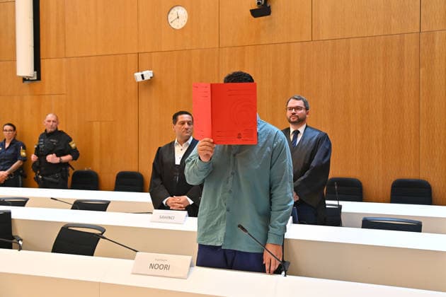 Der Angeklagte im Verhandlungssaal, verbirgt sein Gesicht hinter einem Schnellhefter. Urteil im Strafverfahren gegen Farhad Noori wegen Mordes u.a.(Seidlstrasse) am 06.08.2026 vor dem Oberlandesgericht Muenchen