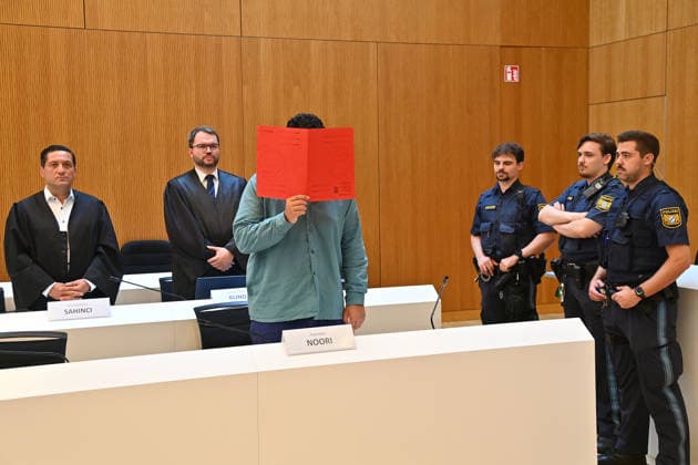 Der Angeklagte im Verhandlungssaal, verbirgt sein Gesicht hinter einem Schnellhefter. Urteil im Strafverfahren gegen Farhad Noori wegen Mordes u.a.(Seidlstrasse) am 06.08.2026 vor dem Oberlandesgericht Muenchen