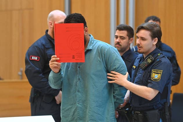 Der Angeklagte wird von Justizbeamten in den Verhandlungssaal gefuehrt. Urteil im Strafverfahren gegen Farhad Noori wegen Mordes u.a.(Seidlstrasse) am 06.08.2026 vor dem Oberlandesgericht Muenchen
