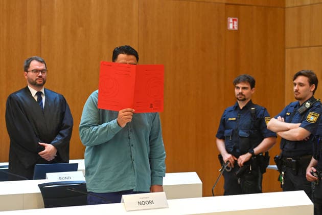 Der Angeklagte im Verhandlungssaal, verbirgt sein Gesicht hinter einem Schnellhefter.Hinten:sein Verteidiger RA Johann BUND. Urteil im Strafverfahren gegen Farhad Noori wegen Mordes u.a.(Seidlstrasse) am 06.08.2026 vor dem Oberlandesgericht Muenchen