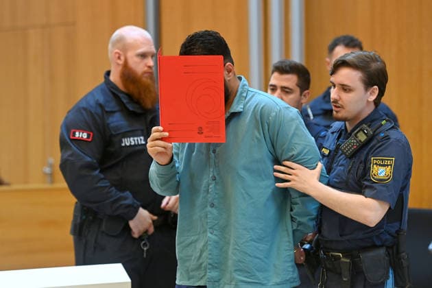 Der Angeklagte wird von Justizbeamten in den Verhandlungssaal gefuehrt. Urteil im Strafverfahren gegen Farhad Noori wegen Mordes u.a.(Seidlstrasse) am 06.08.2026 vor dem Oberlandesgericht Muenchen