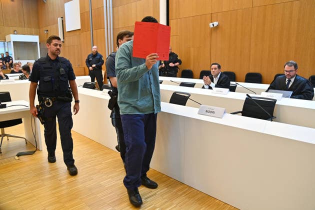 Der Angeklagte wird von Justizbeamten in den Verhandlungssaal gefuehrt. Urteil im Strafverfahren gegen Farhad Noori wegen Mordes u.a.(Seidlstrasse) am 06.08.2026 vor dem Oberlandesgericht Muenchen