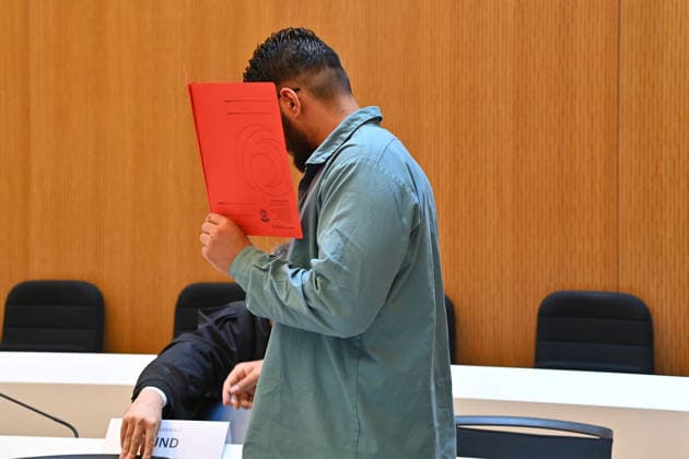 Der Angeklagte im Verhandlungssaal, verbirgt sein Gesicht hinter einem Schnellhefter. Urteil im Strafverfahren gegen Farhad Noori wegen Mordes u.a.(Seidlstrasse) am 06.08.2026 vor dem Oberlandesgericht Muenchen