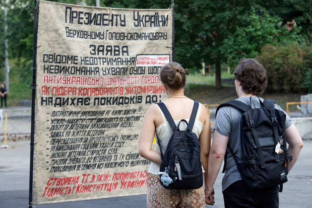 Man And Woman Read Text On Placard At Rally Against Dismissal Of Mykhailo Fedorov - Kyiv A man and a woman read a text on a placard during a peaceful protest against the dismissal of Mykhailo Fedorov from the post of Ukraine s Defence Minister in Ivana Franka Square outside the Ivan Franko National Academic Drama Theatre, close to the Office of the President, Kyiv, Ukraine on August 6, 2026. Large-scale cardboard rallies in support of former Defence Minister Mykhailo Fedorov have been held in Kyiv and other cities across Ukraine for 22 consecutive days. On July 14, 2026, the Ukrainian Parliament accepted the resignation of Prime Minister Yuliia Svyrydenko, leading to the resignation of the Cabinet. On July 15, 2026, President Volodymyr Ze  Copyright: xUkrinform ABACAx